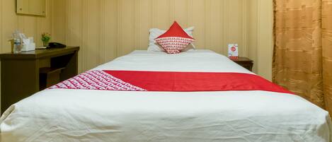 Habitación de hotel con cama, escritorio, teléfono, un cuadro en la pared y una cortina.