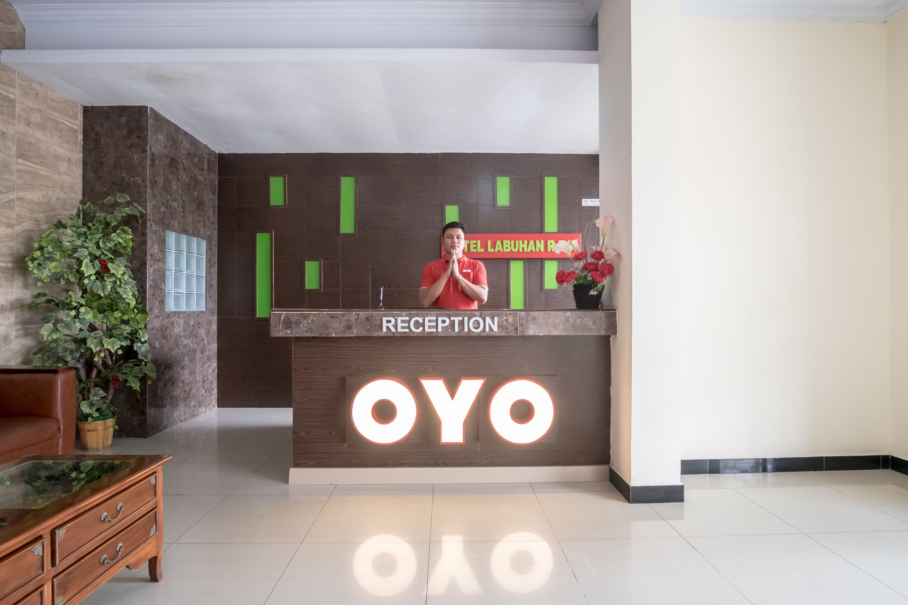 A reception desk with a sign reading "RECEPTION" and "OYO HOTEL LABUHAN RO".