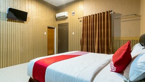 A hotel room with a bed, a flat-screen TV mounted on the wall, an air conditioning unit, a shower curtain, and a towel rack. - Hotel O Medan Near Gajah Mada formerly Hotel Indah Raya (Medan)