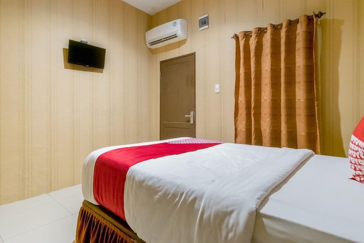 Een hotelkamer met een bed, een televisie, een airconditioning en een deur.