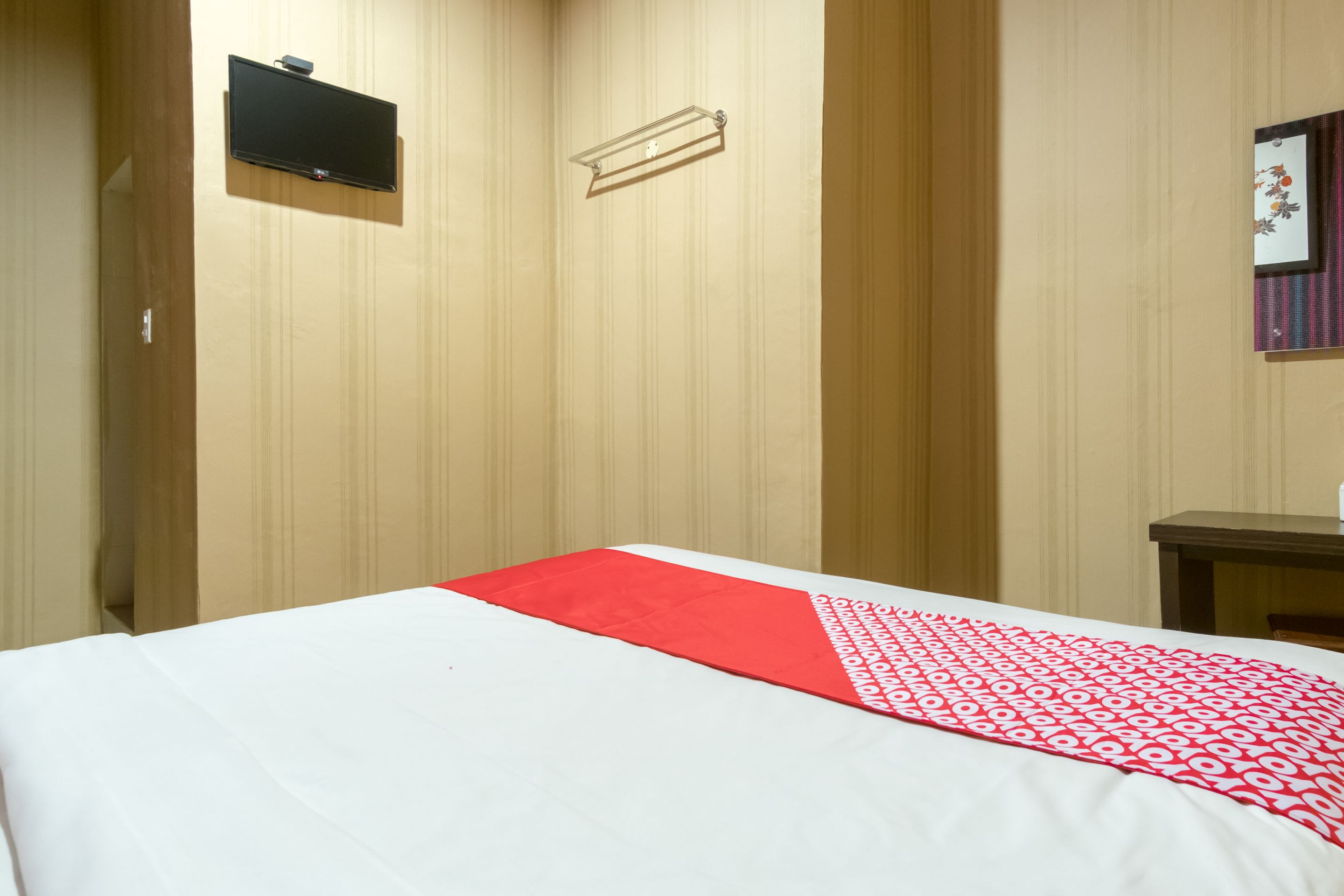 Une chambre d’hôtel avec un lit, un téléviseur fixé au mur et une petite table.