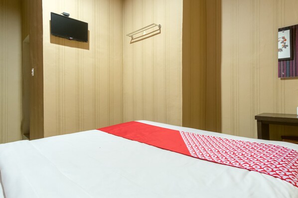 Una habitación de hotel con una cama, un televisor en la pared y una mesita.