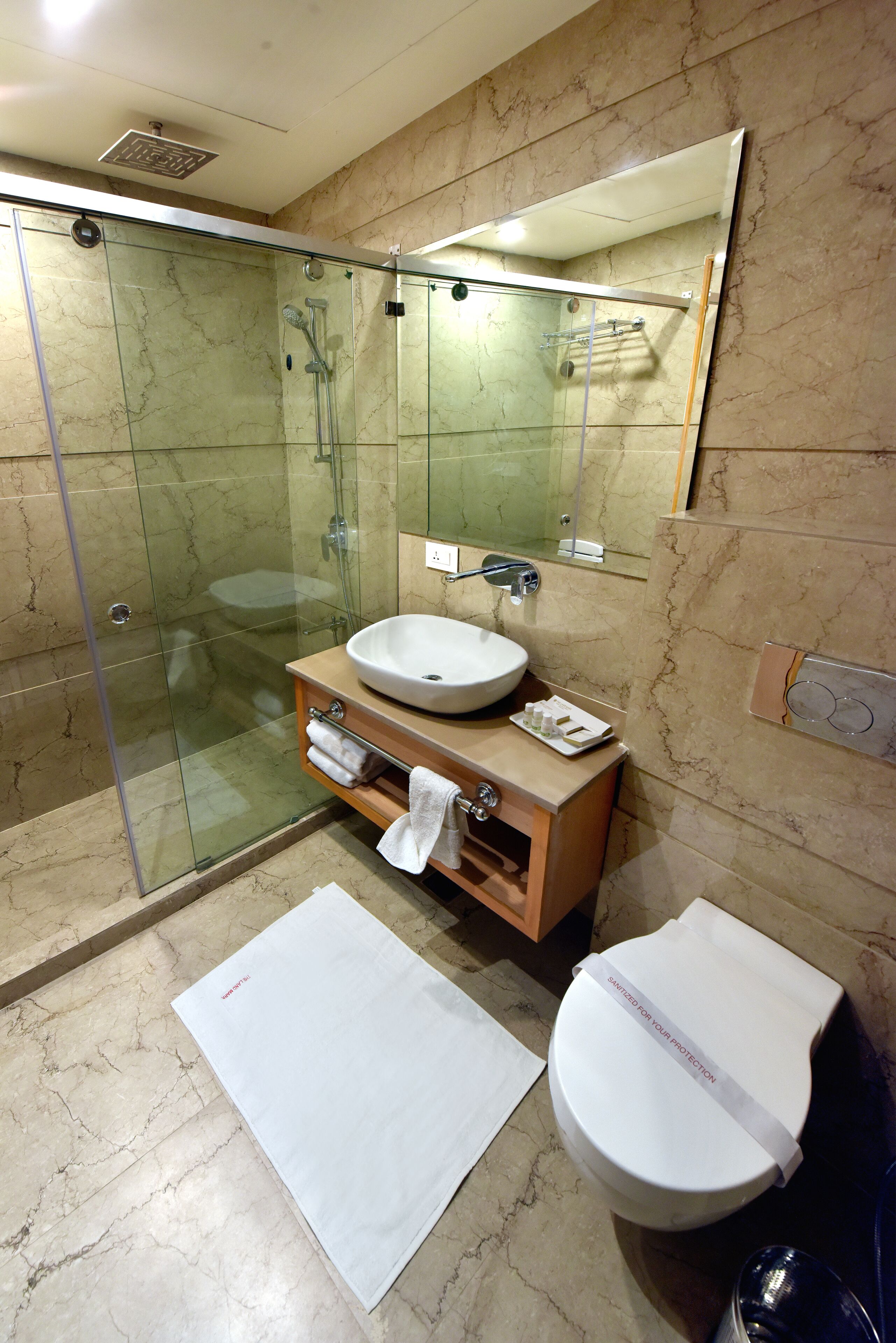 A modern bathroom with a glass-enclosed shower, a sink, and a toilet.