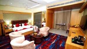 A hotel room with a bed, two armchairs, a coffee table, and a TV. - Hotel Landmark Near Golden Temple (Amritsar)