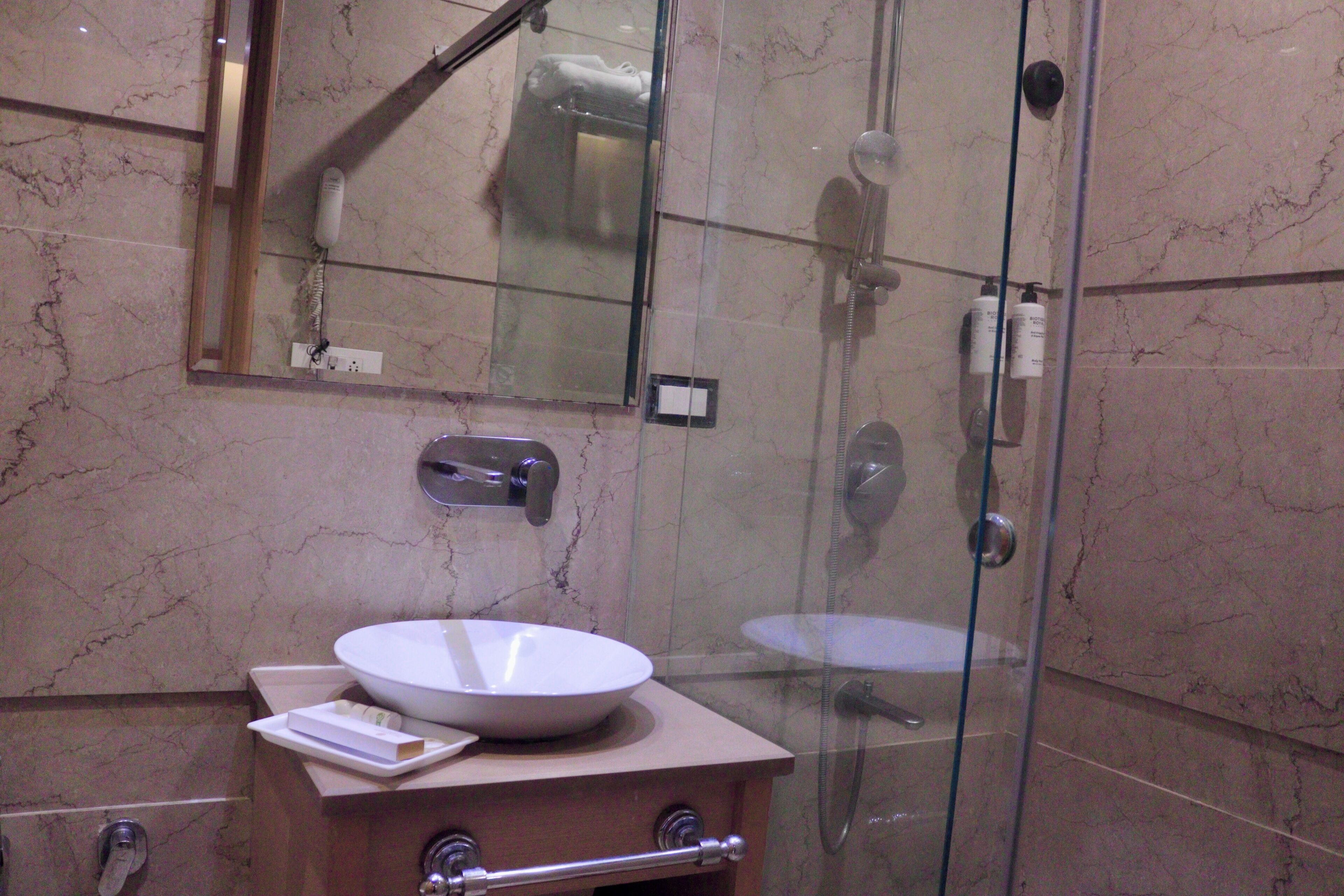 A bathroom with a glass-enclosed shower, a white sink, and a mirror above the sink.