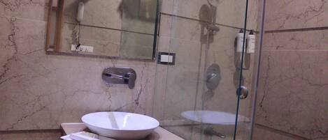A bathroom with a glass-enclosed shower, a white sink, and a mirror above the sink.