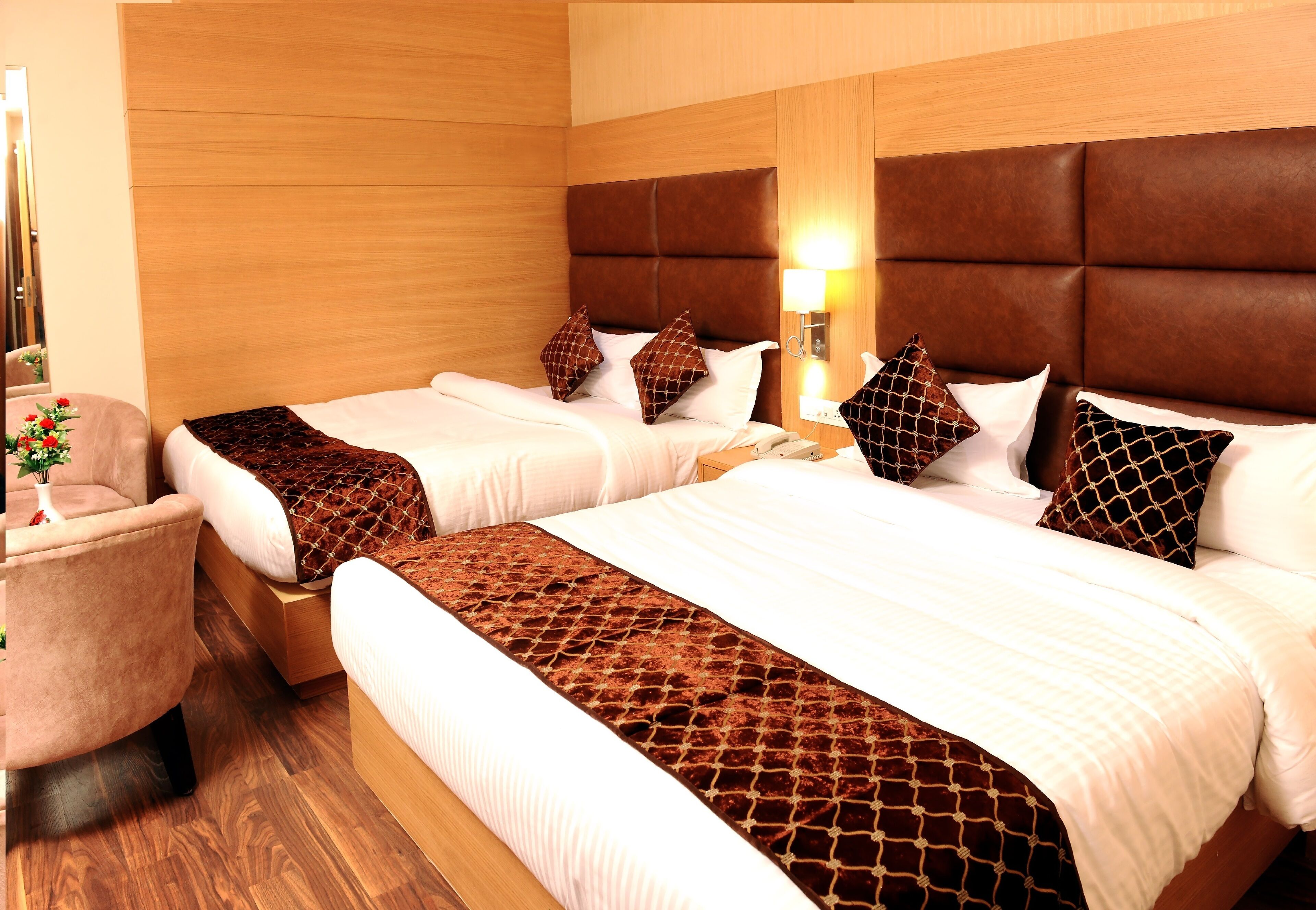 A hotel room with two beds, a wooden headboard, a nightstand, and a chair.