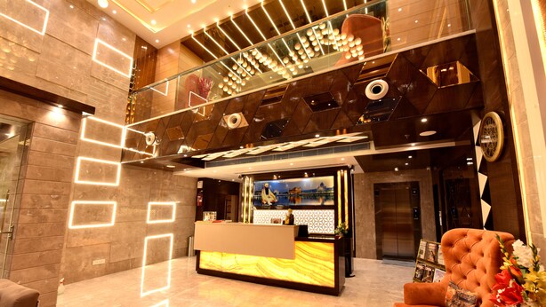 A modern lobby with a reception desk, a plush seating area, a staircase, and a decorative ceiling. - Hotel Landmark Near Golden Temple (Amritsar)