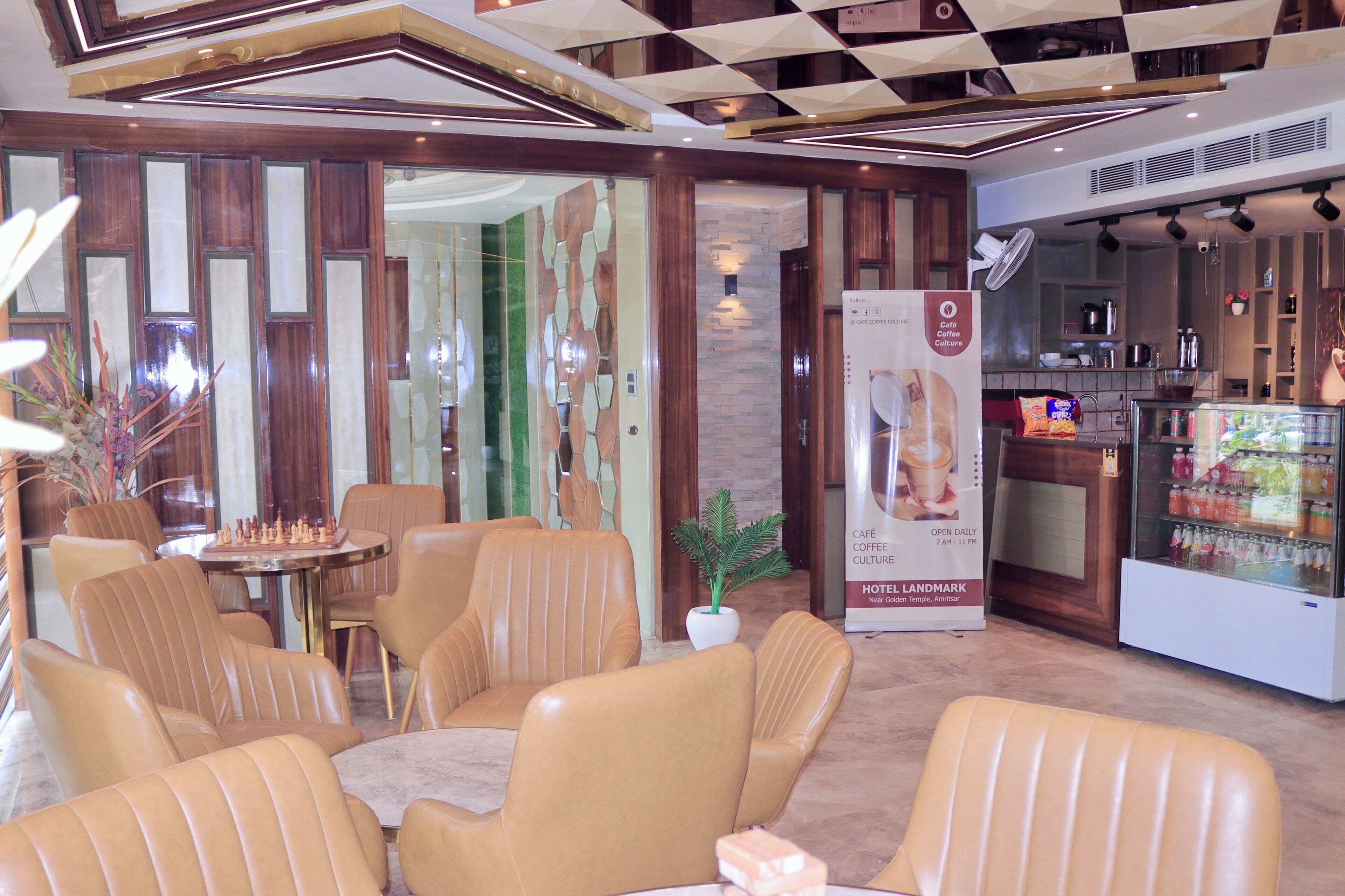 A hotel lobby with leather chairs, a coffee bar, and a refrigerator with beverages.