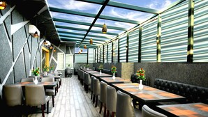 A modern restaurant with long tables and chairs, a wooden floor, and a glass ceiling. - Hotel Landmark Near Golden Temple (Amritsar)