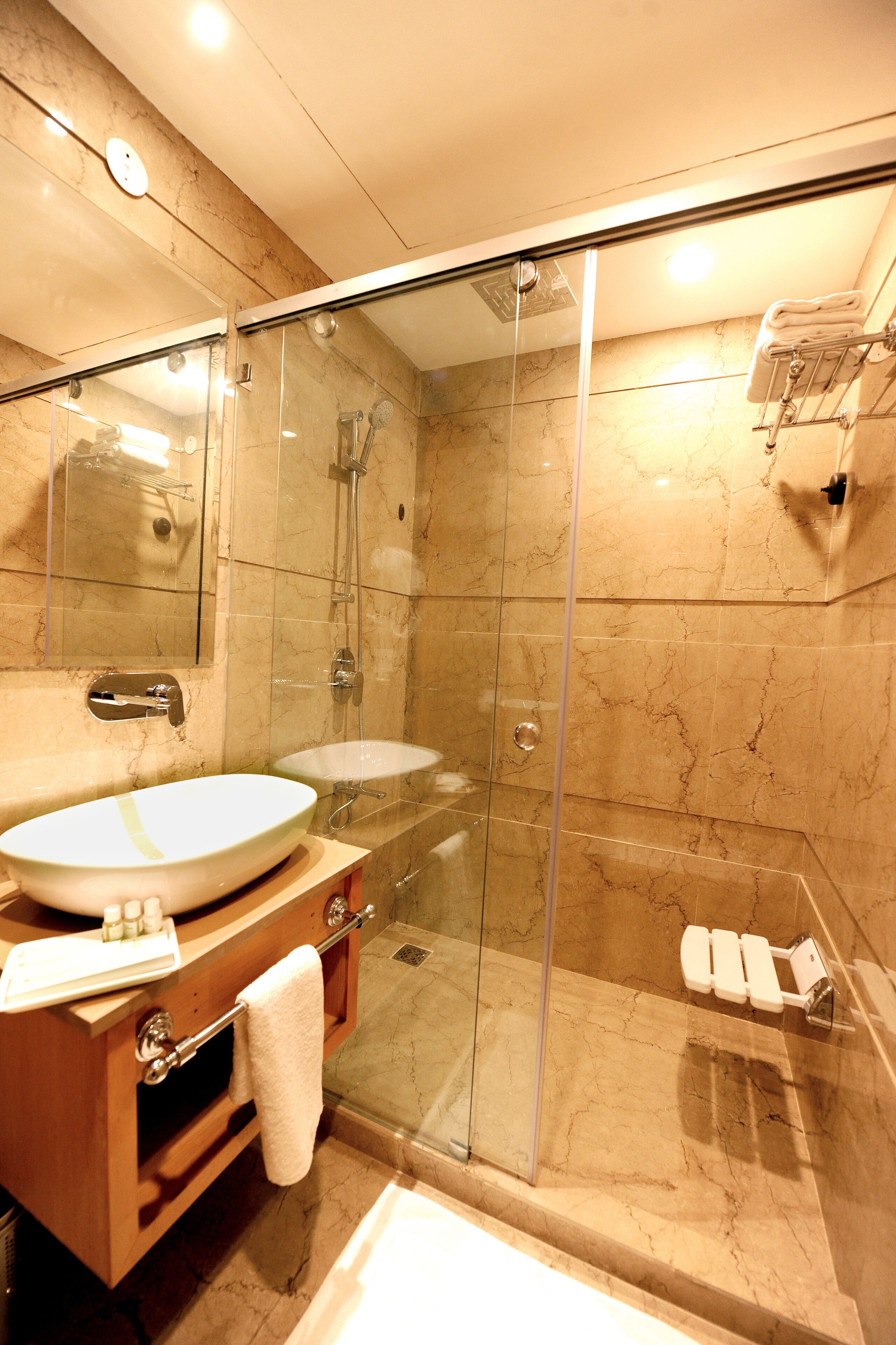 A modern bathroom with a glass-enclosed shower, a wooden vanity with a large sink, and a mirror above the vanity.