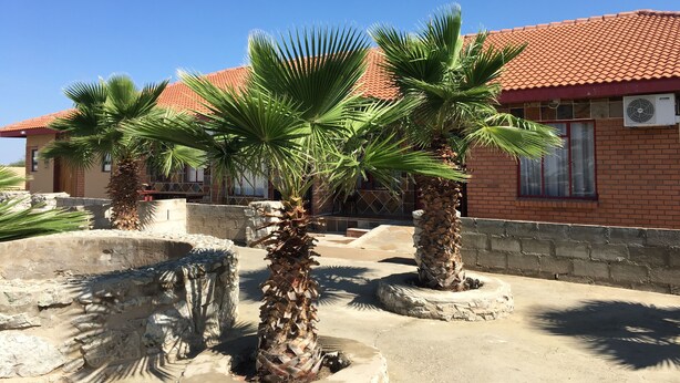 Un edificio con techo de tejas rojas y palmeras al frente.