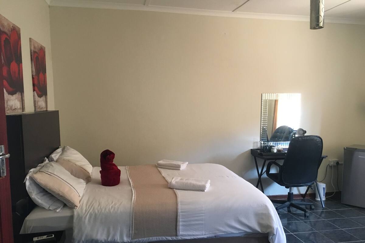 Ein Hotelzimmer mit einem Bett, einem Schreibtisch mit Computer und einem Sessel.