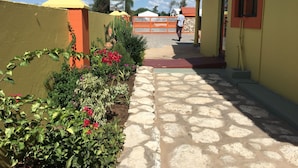 Un camino pavimentado que lleva a un edificio con fachada amarilla y tejado rojo.