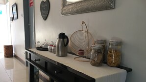 A kitchenette with a coffee maker, jars, and a fan. - Yana Bed & Breakfast (Gaborone)