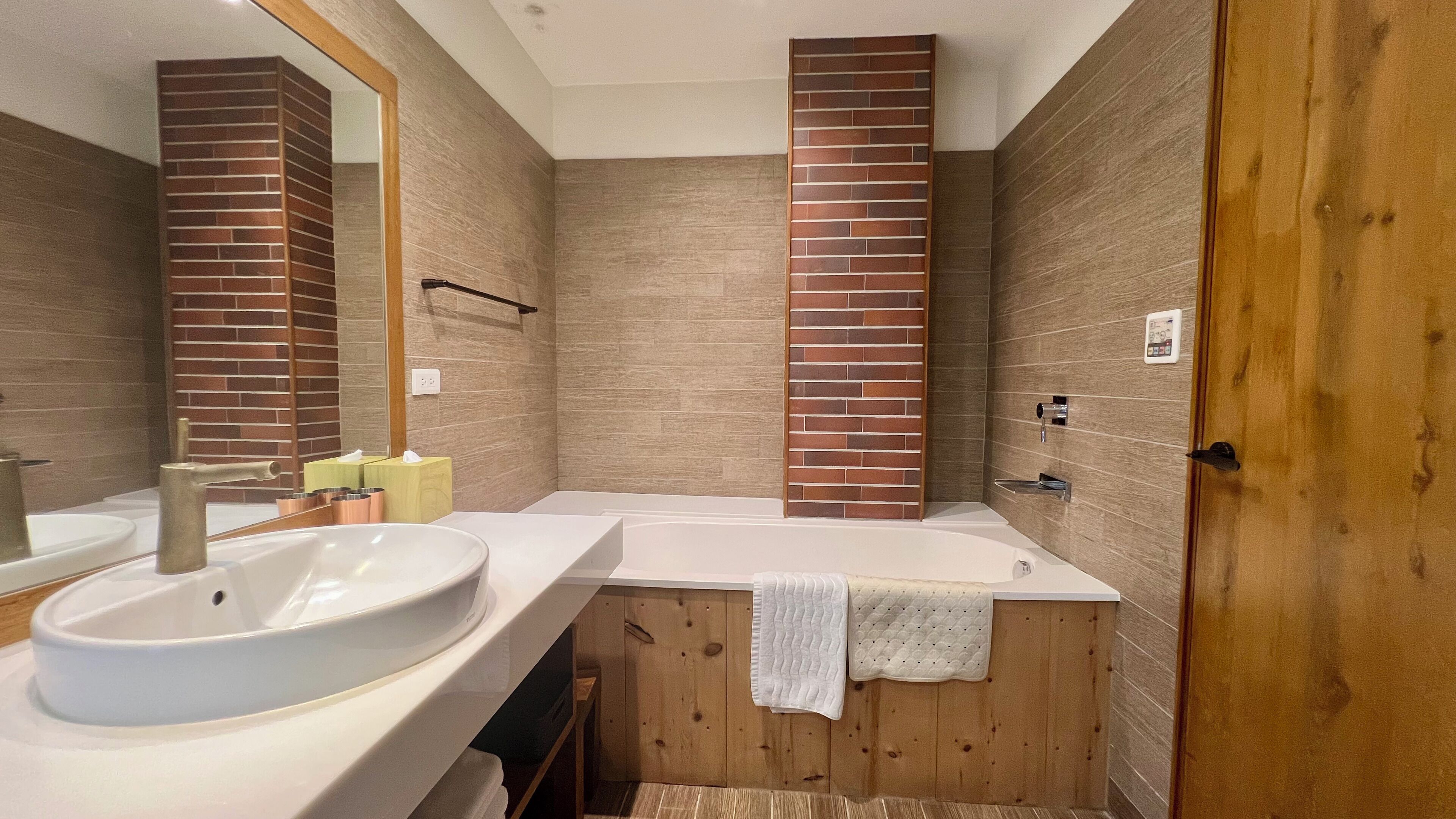 Une salle de bain moderne avec un grand lavabo, une baignoire et un meuble-lavabo en bois.