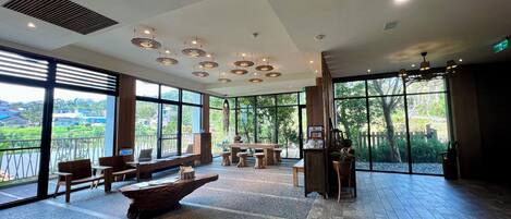 A spacious room with large windows, a wooden table, and several chairs.