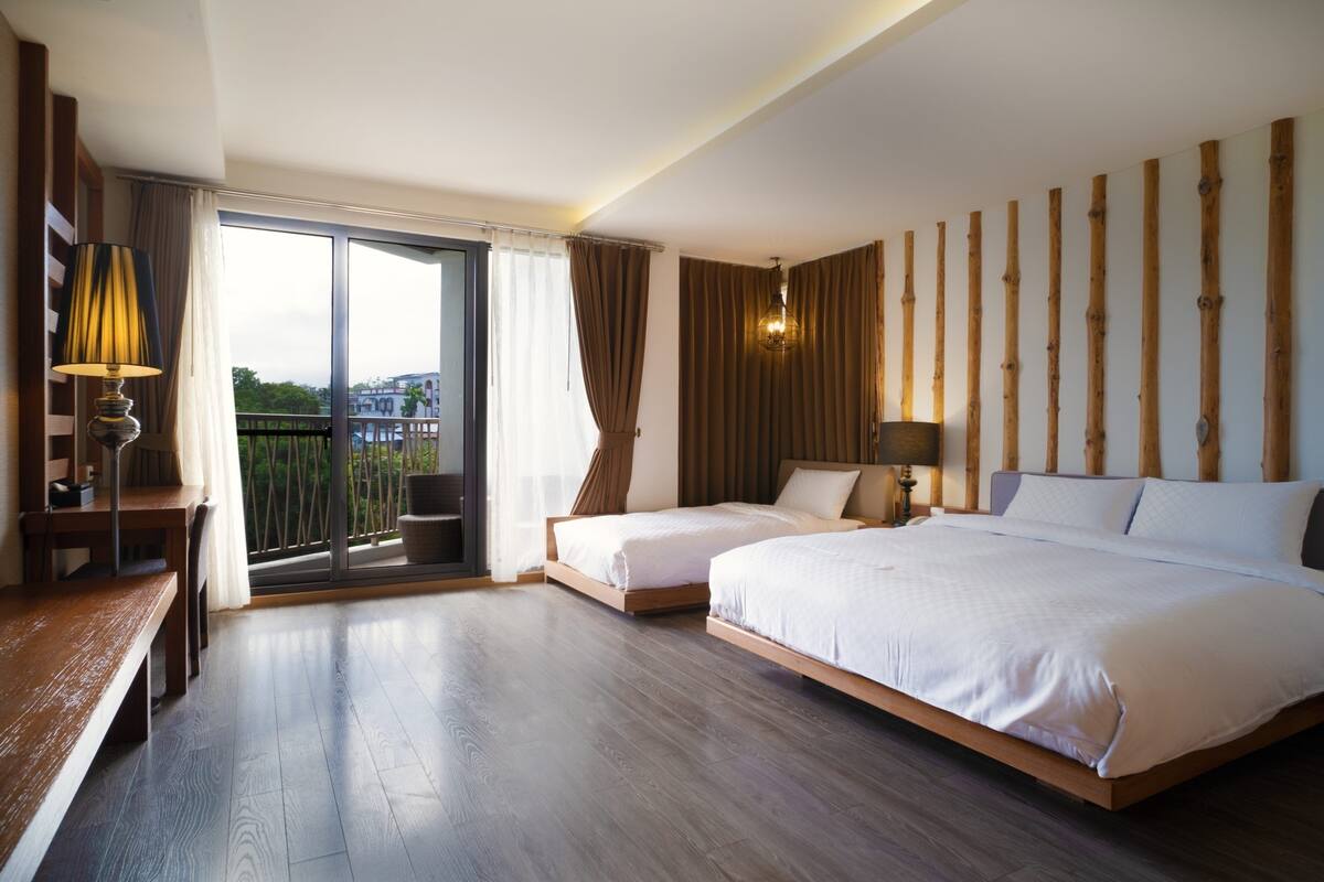 Una habitación de hotel con una cama grande, un escritorio y un balcón con vistas.