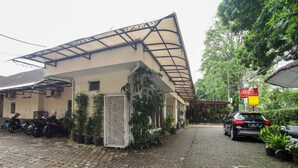 A building with a covered entrance, potted plants, and parked motorcycles. - Guest House Near by Kebun Raya Bogor (Bogor)