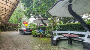 A paved outdoor area with a car parked, a bench, and potted plants. - Guest House Near by Kebun Raya Bogor (Bogor)