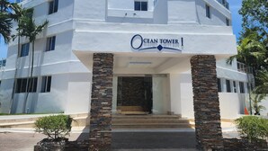 Un hotel a più piani chiamato Ocean Tower, dal design moderno, con un ingresso ben visibile caratterizzato da colonne in pietra e una facciata in vetro.