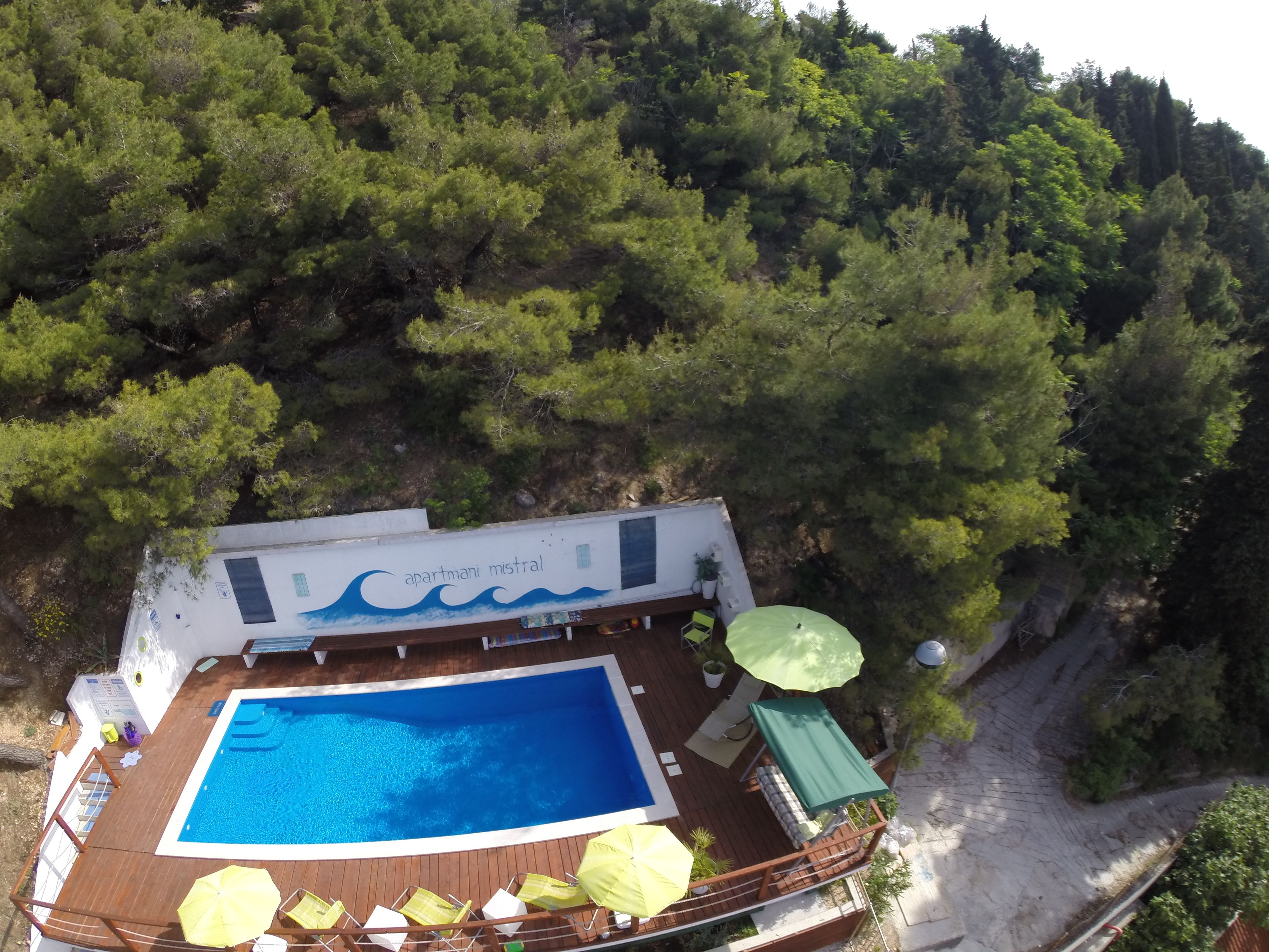 A rooftop pool with a wooden deck, lounge chairs, and umbrellas.