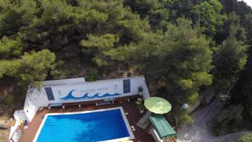 A rooftop pool with a wooden deck, lounge chairs, and umbrellas.