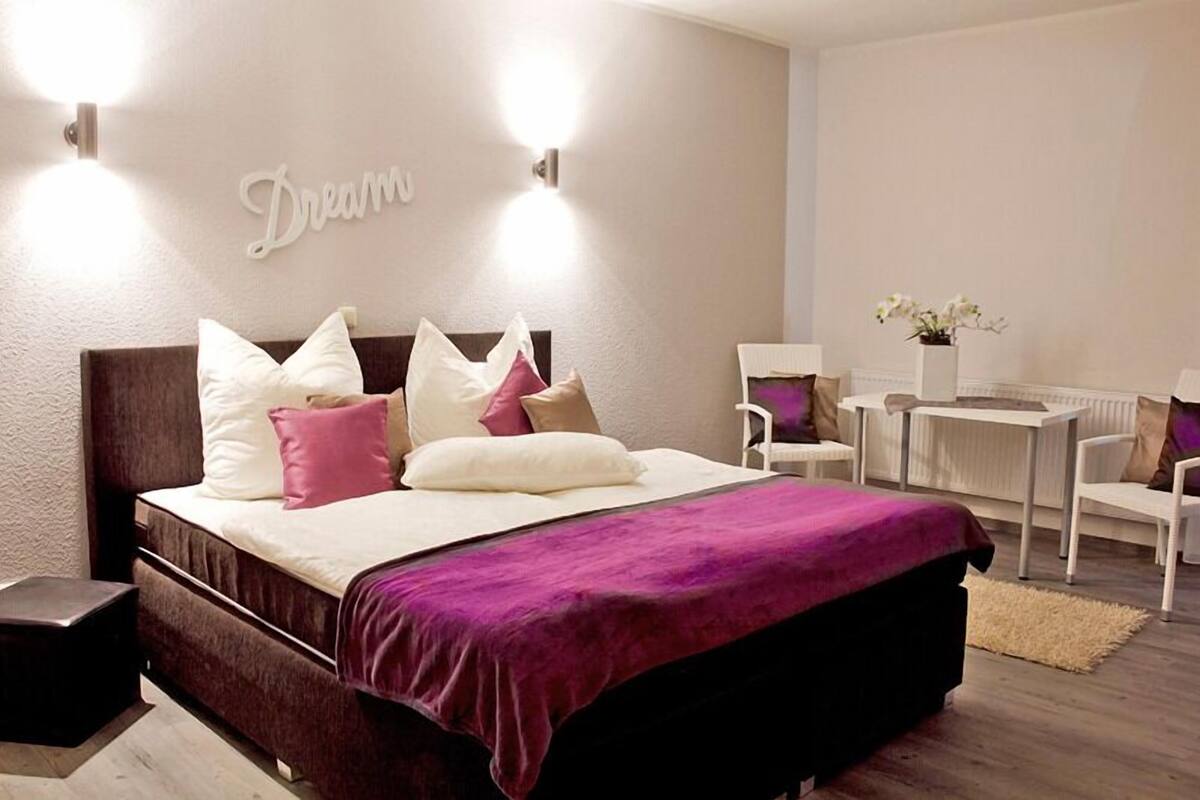 Un dormitorio moderno con una cama grande, mesitas de noche, un escritorio y una silla.
