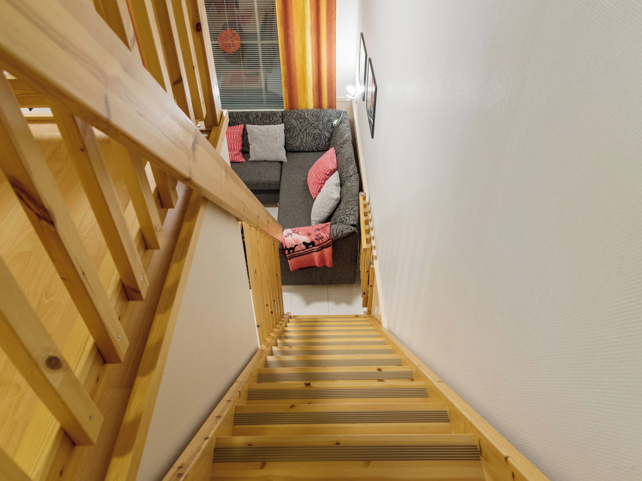 Eine Holztreppe führt zu einem Wohnbereich mit einer Couch und Kissen.