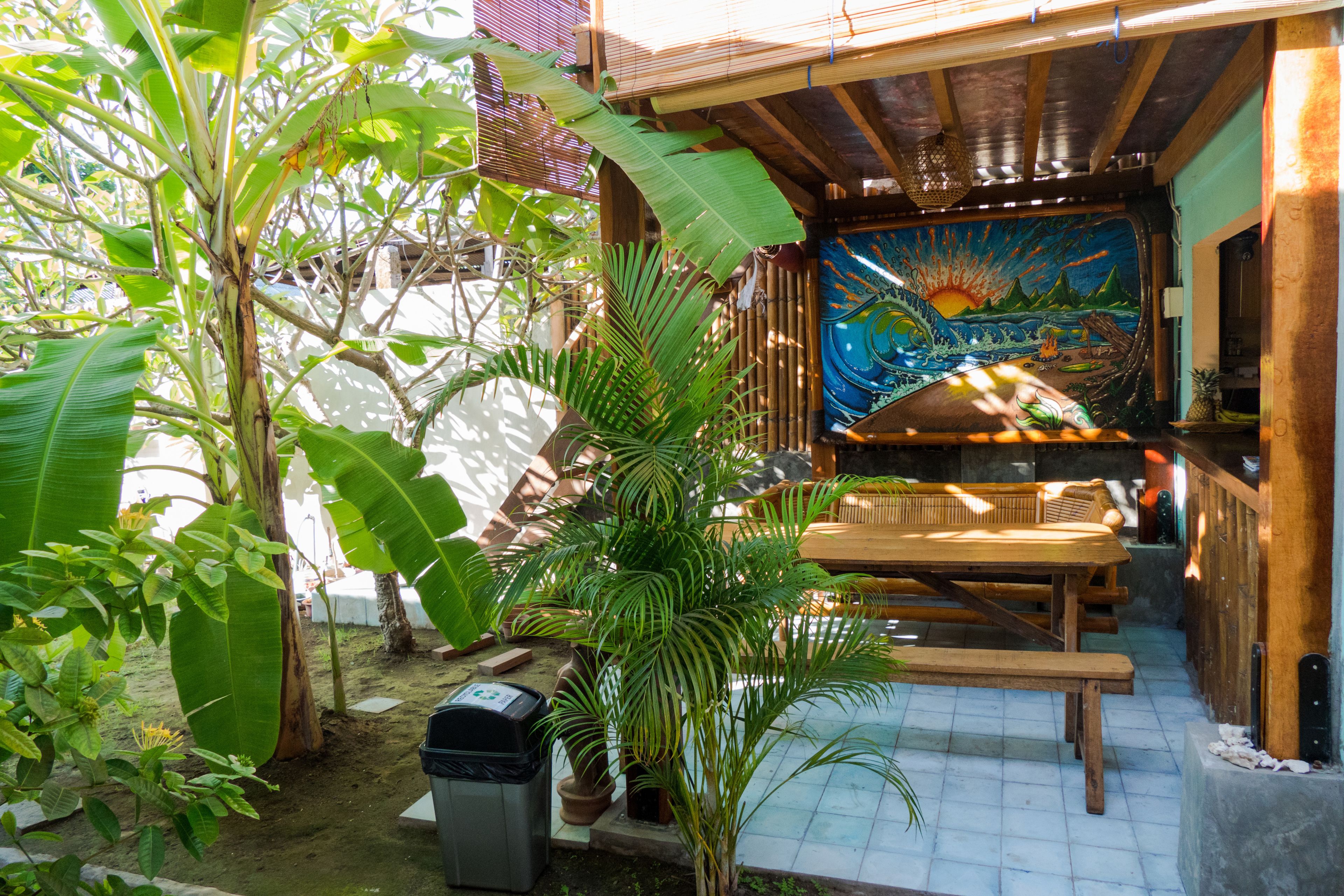 A wooden deck with a mural, surrounded by lush greenery and a tiled floor.