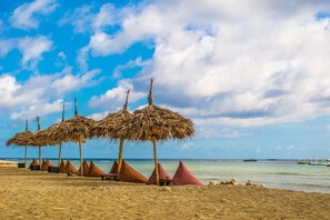 Ubicación cercana a la playa, arena blanca y toallas de playa