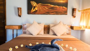 Quarto com uma cama grande, uma pintura de Buda e cabeceira de madeira.