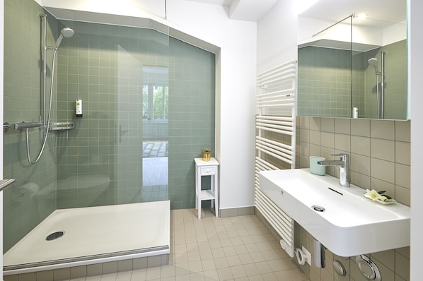 Une salle de bain moderne avec une douche à parois de verre, un meuble-lavabo blanc et un petit tabouret.