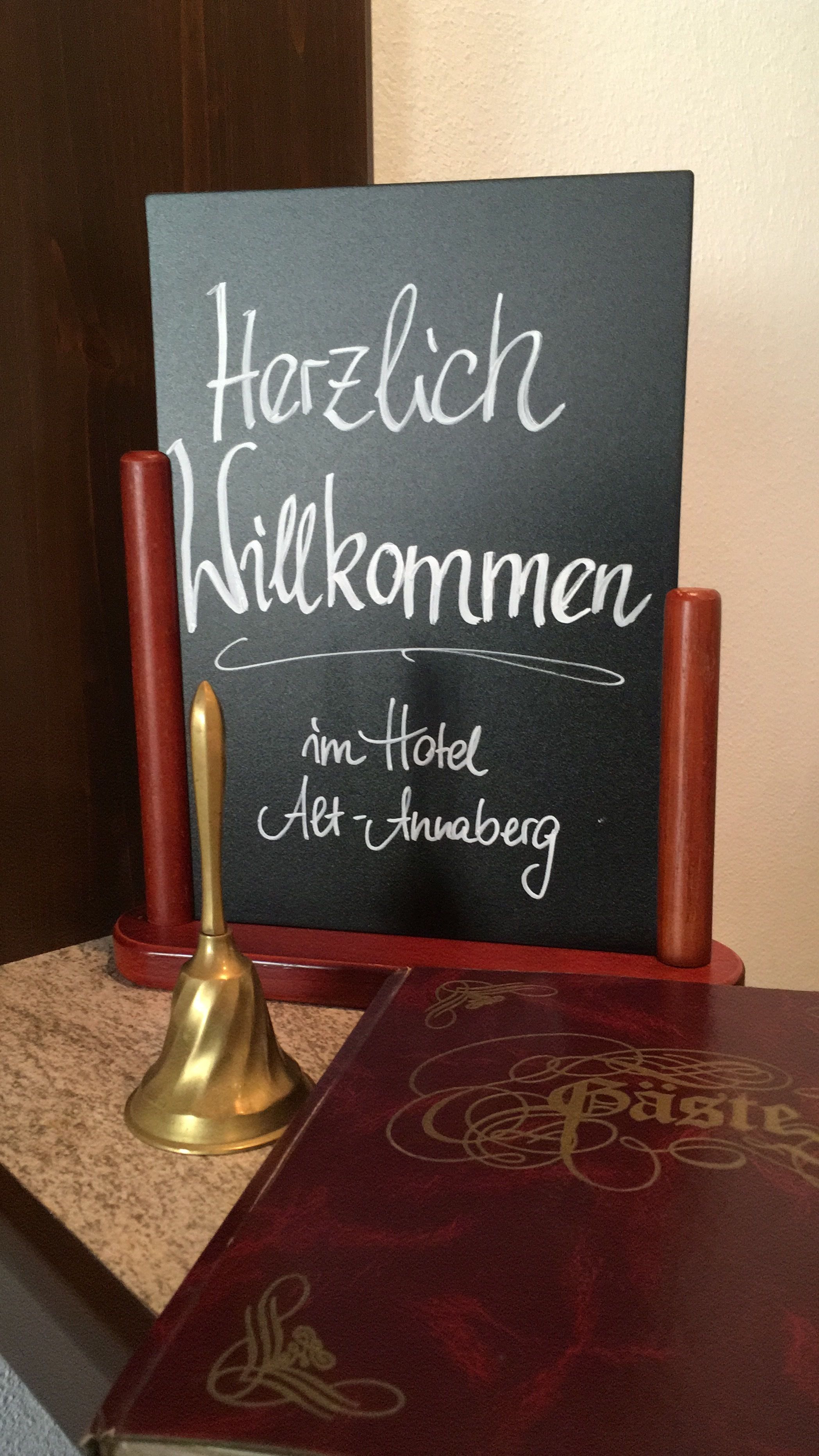 A welcome sign with the text "Herzlich Willkommen im Hotel Alt-Anaberg" in a hotel setting.