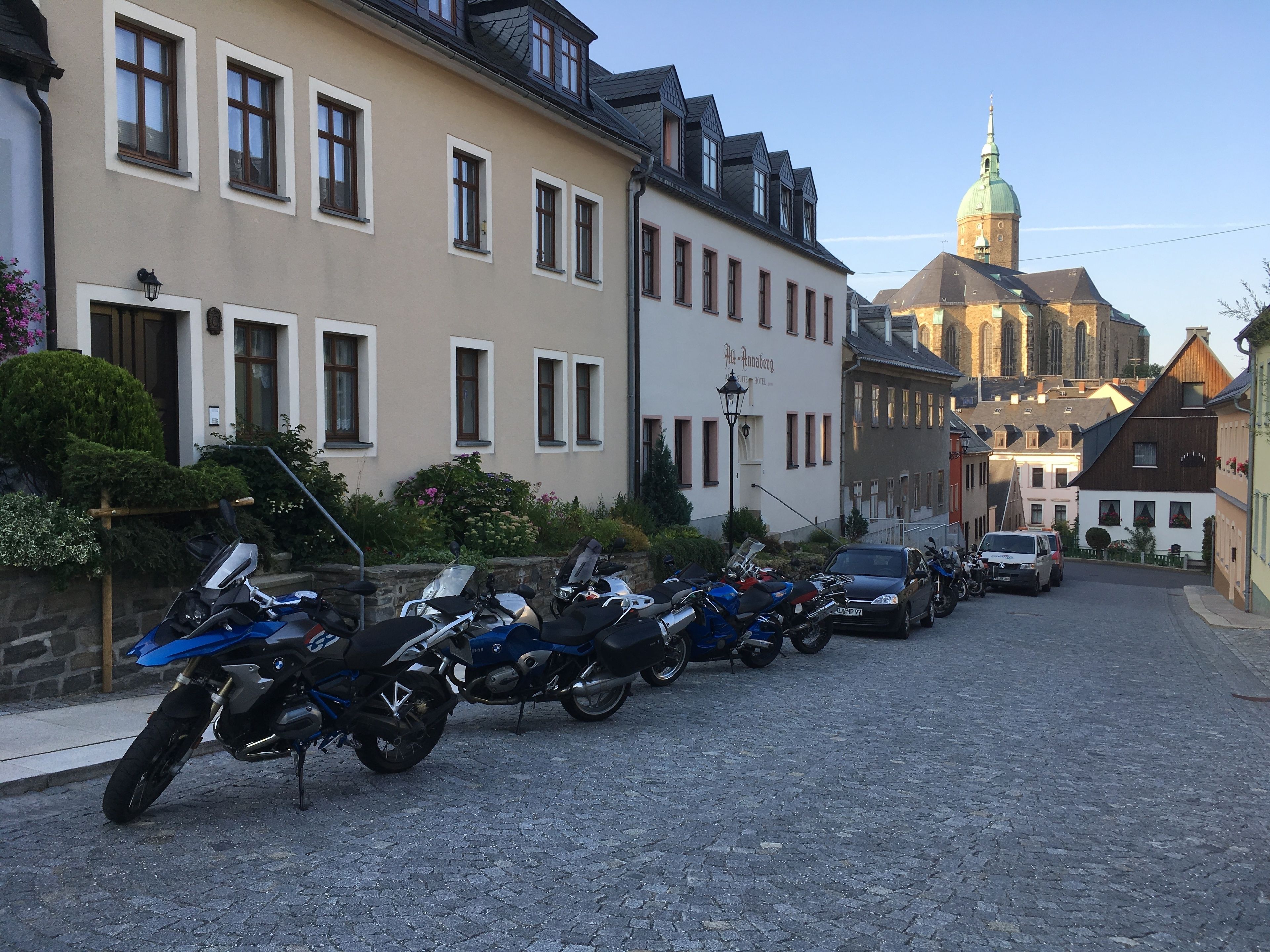 Una calle adoquinada bordeada de motocicletas estacionadas y edificios de estilo europeo clásico.