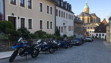 Una calle adoquinada bordeada de motocicletas estacionadas y edificios de estilo europeo clásico.