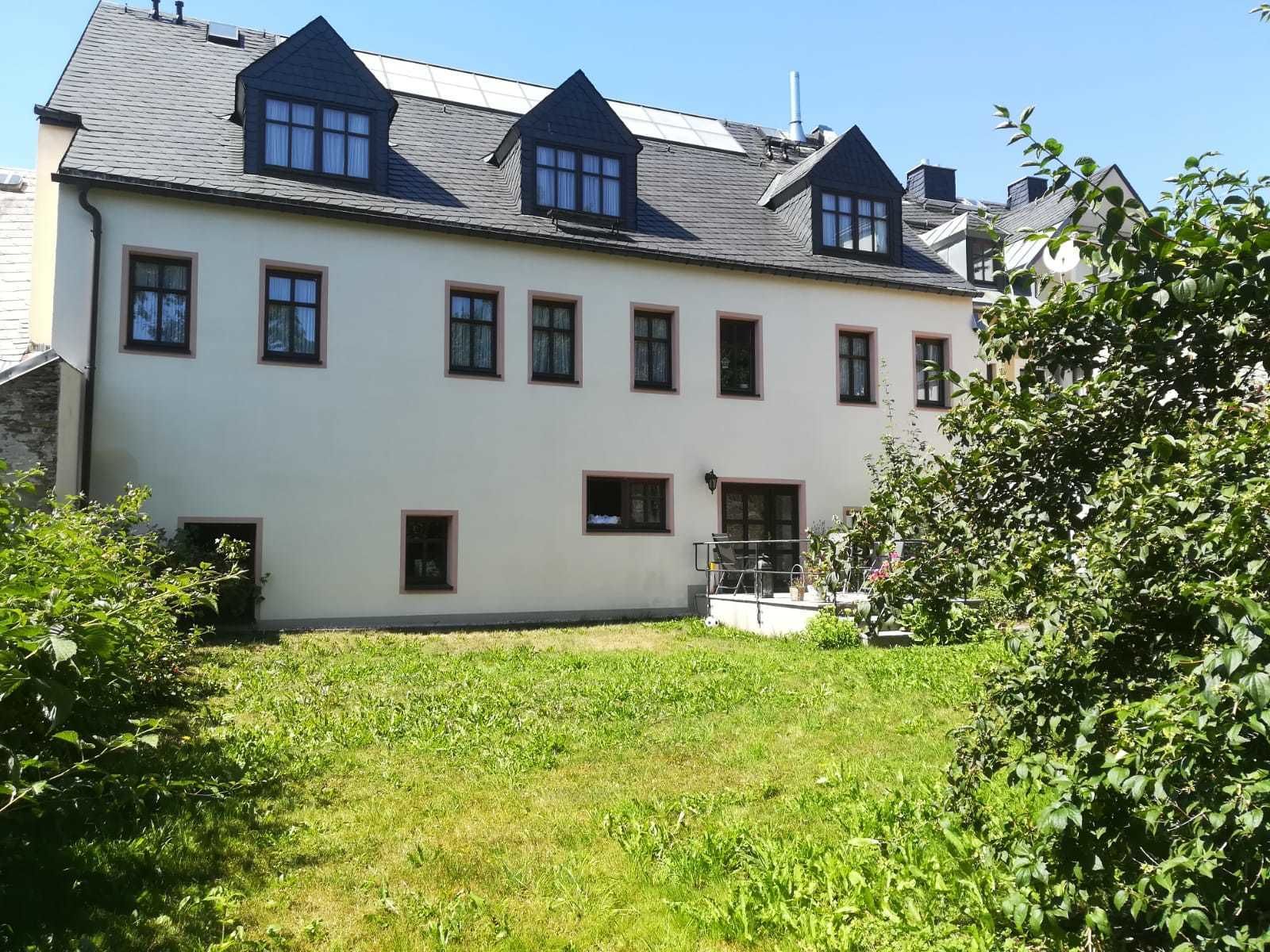 A two-story building with a symmetrical facade, multiple windows, and a small front garden area.