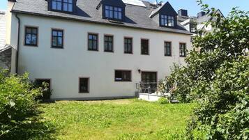 A two-story building with a symmetrical facade, multiple windows, and a small front garden area.