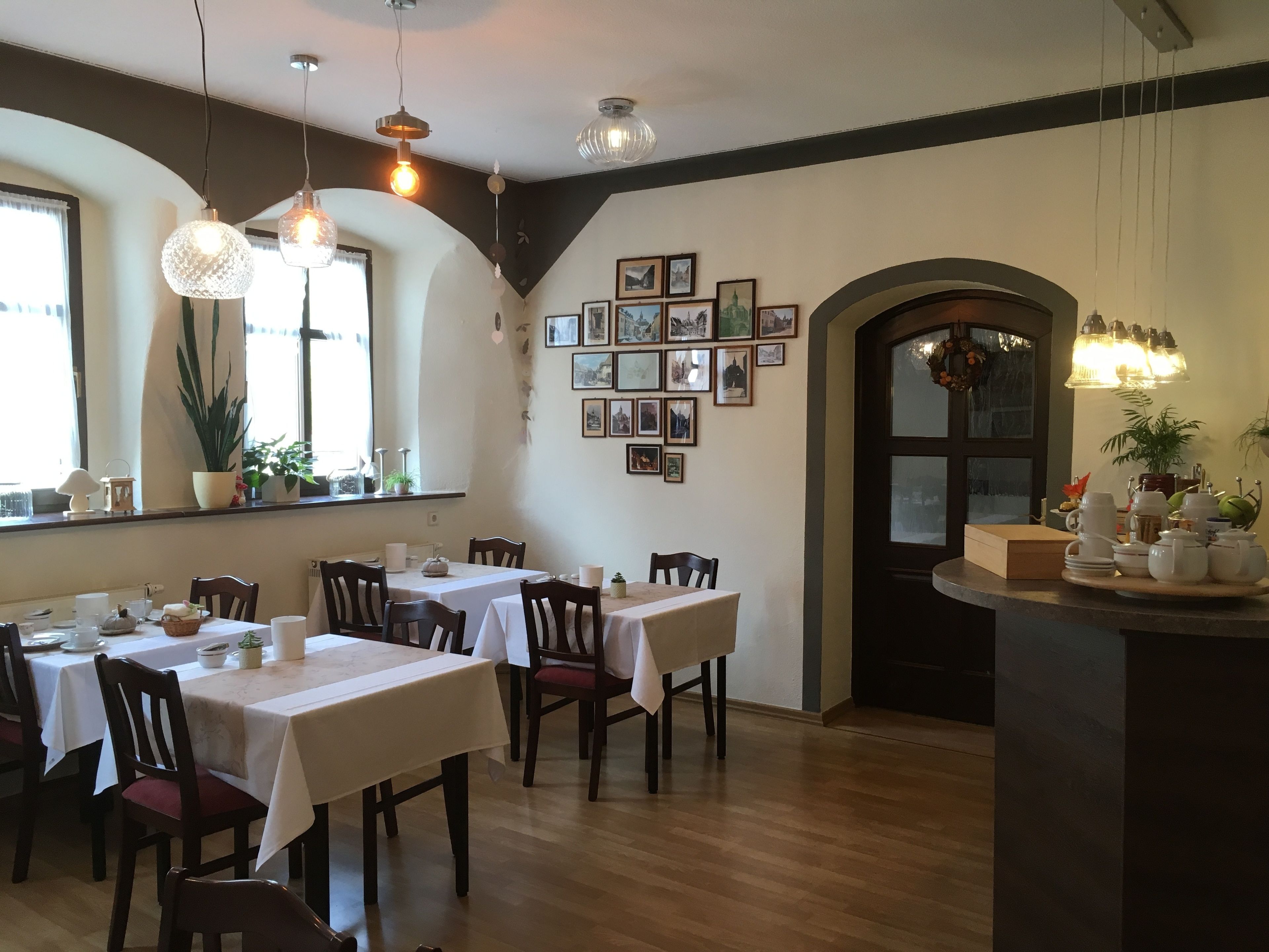 Comedor con mesas dispuestas para cuatro, sillas de madera y una variedad de vajilla.