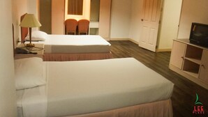 A hotel room with two beds, a desk with a lamp, a television, and a wardrobe. - Lee Place Hotel (Bangkok)