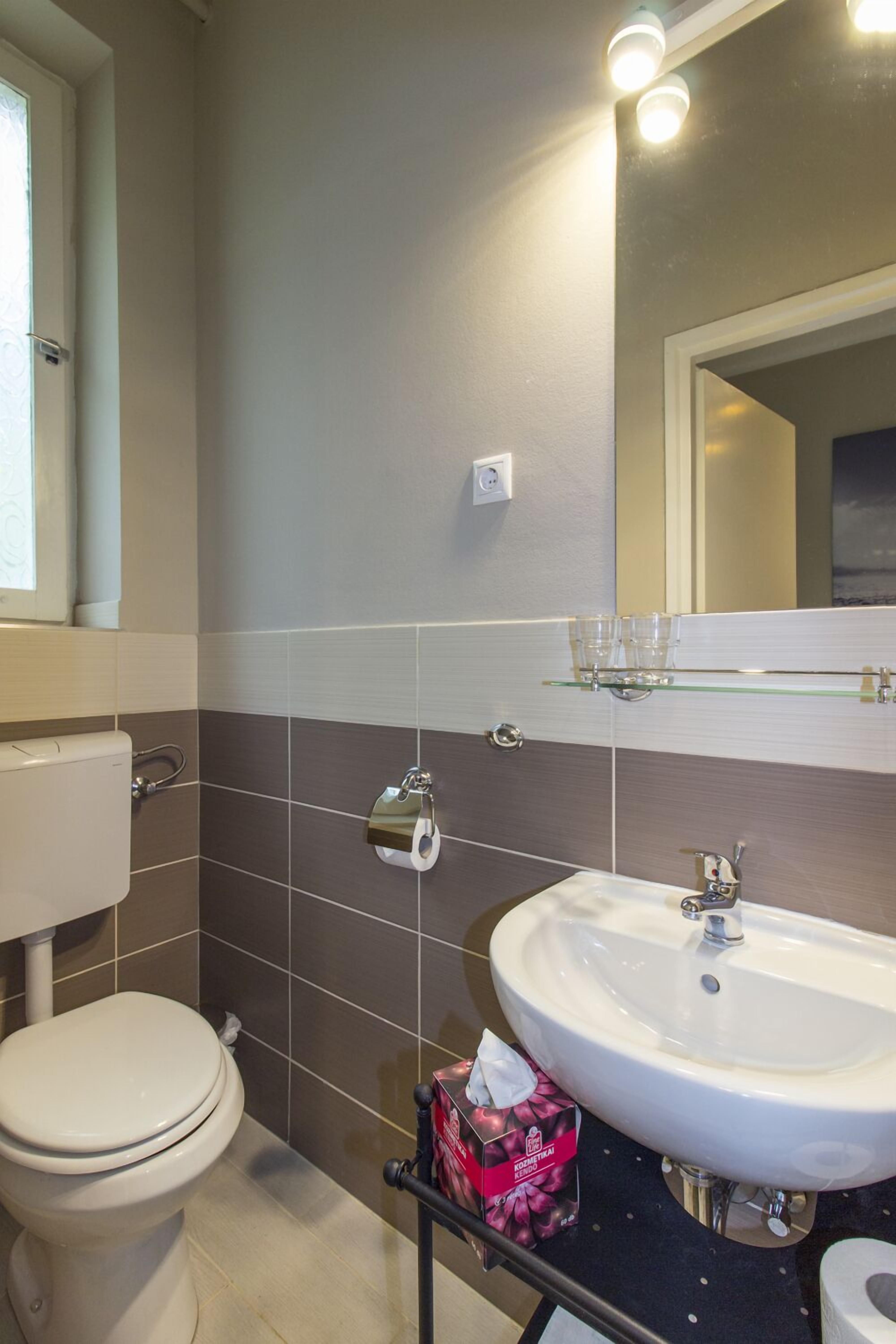 A bathroom with a toilet, sink, and mirror.