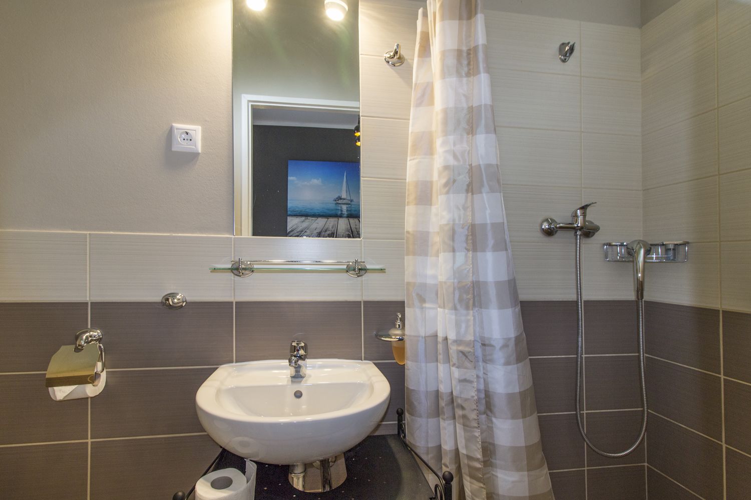 A bathroom with a sink, a shower, a towel rack, and a mirror.