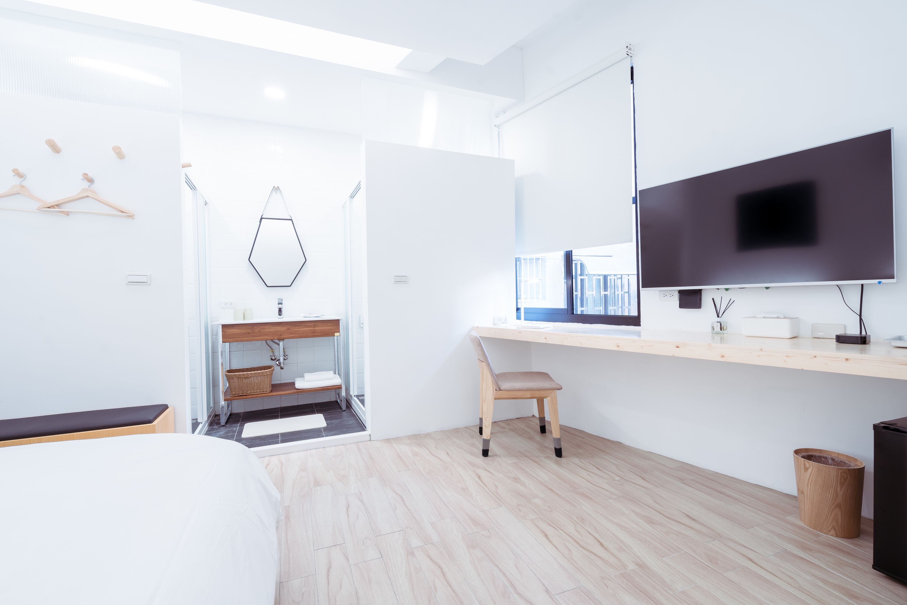 Una camera d'albergo moderna con un letto grande, una scrivania con un computer, una TV e un bagno con doccia e lavandino.
