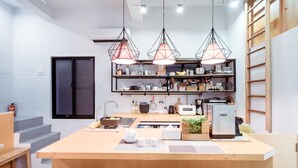 A modern kitchen with a central island, pendant lights, and a built-in refrigerator. - Uns B&B (Kaohsiung)