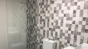 A modern bathroom with a glass-enclosed shower, a toilet, and a sink.