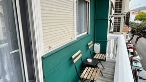 A balcony with a table and chairs, a sliding door, and a view of the street.