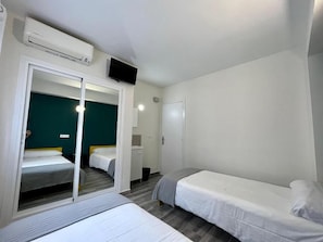 A room with two beds, a television, and a sliding door leading to a bathroom.