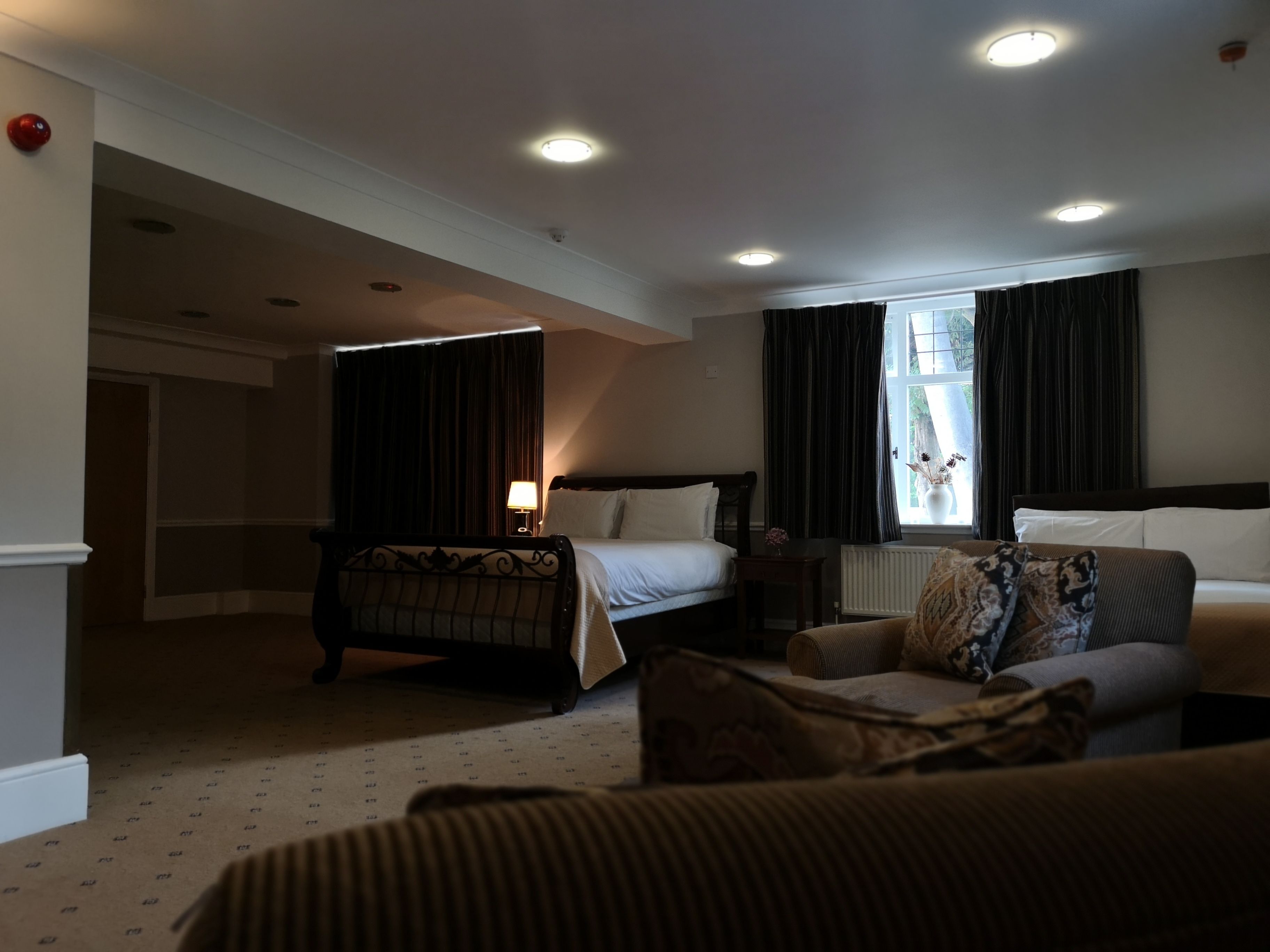 A hotel room with a bed, a sofa, a small table, and a window with curtains.