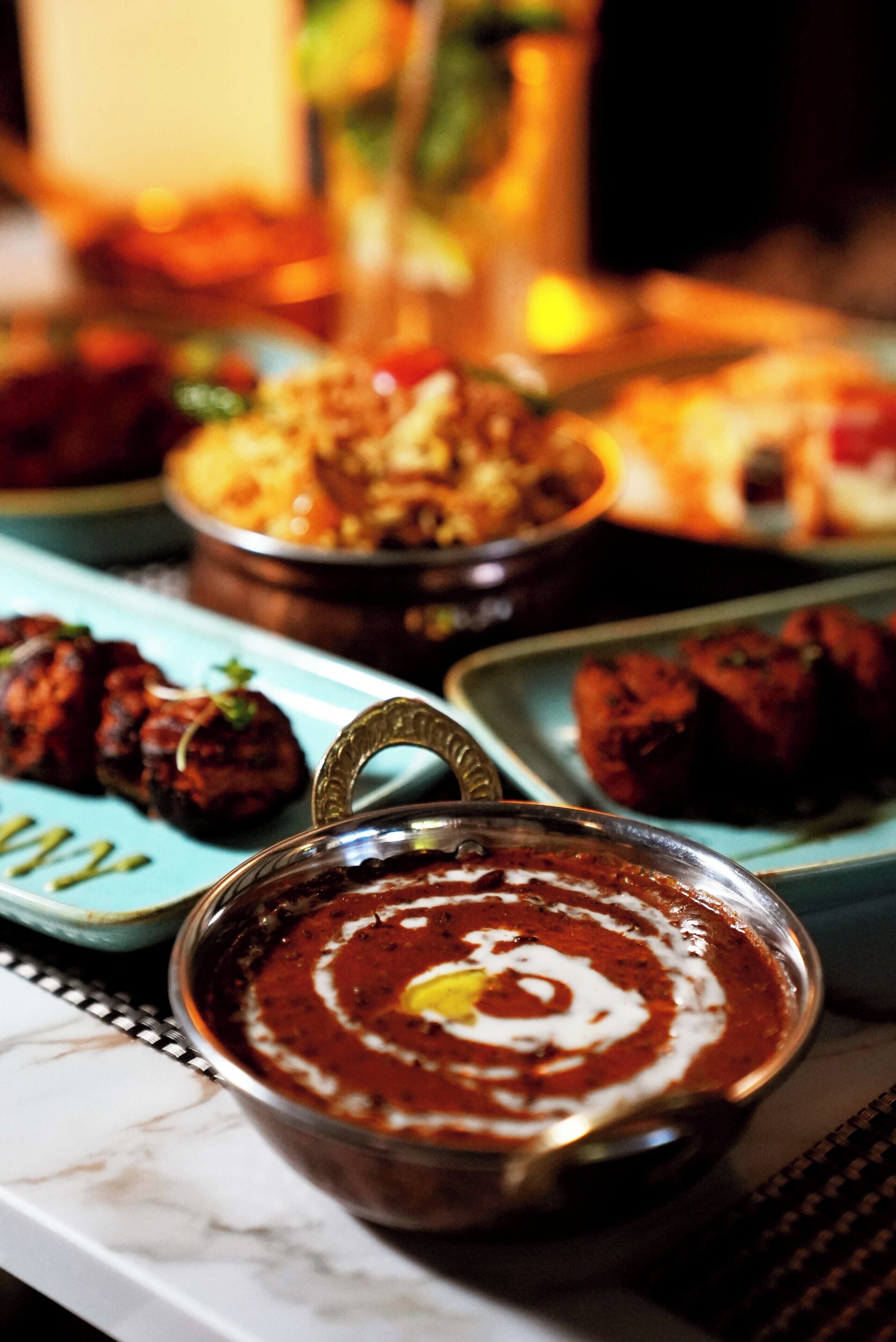 A variety of dishes on a table, including a bowl of red curry with cream.