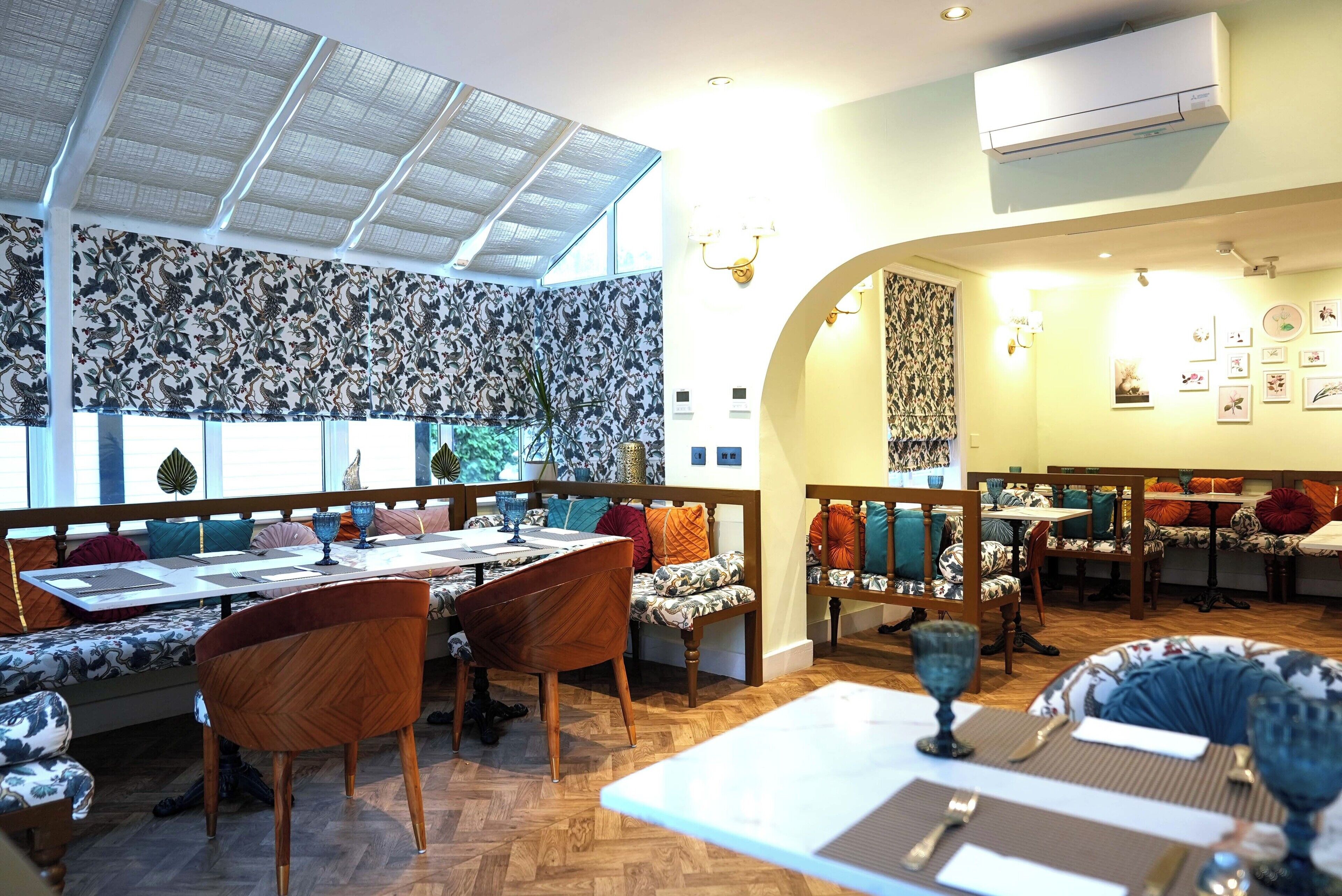 A restaurant with wooden furniture, patterned wallpaper, and a skylight.